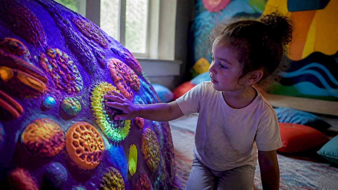 Child's hand exploring textured UV pop art surface