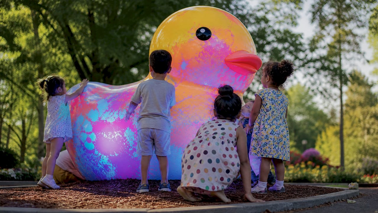 Silhouettes of diverse children near glowing UV artwork