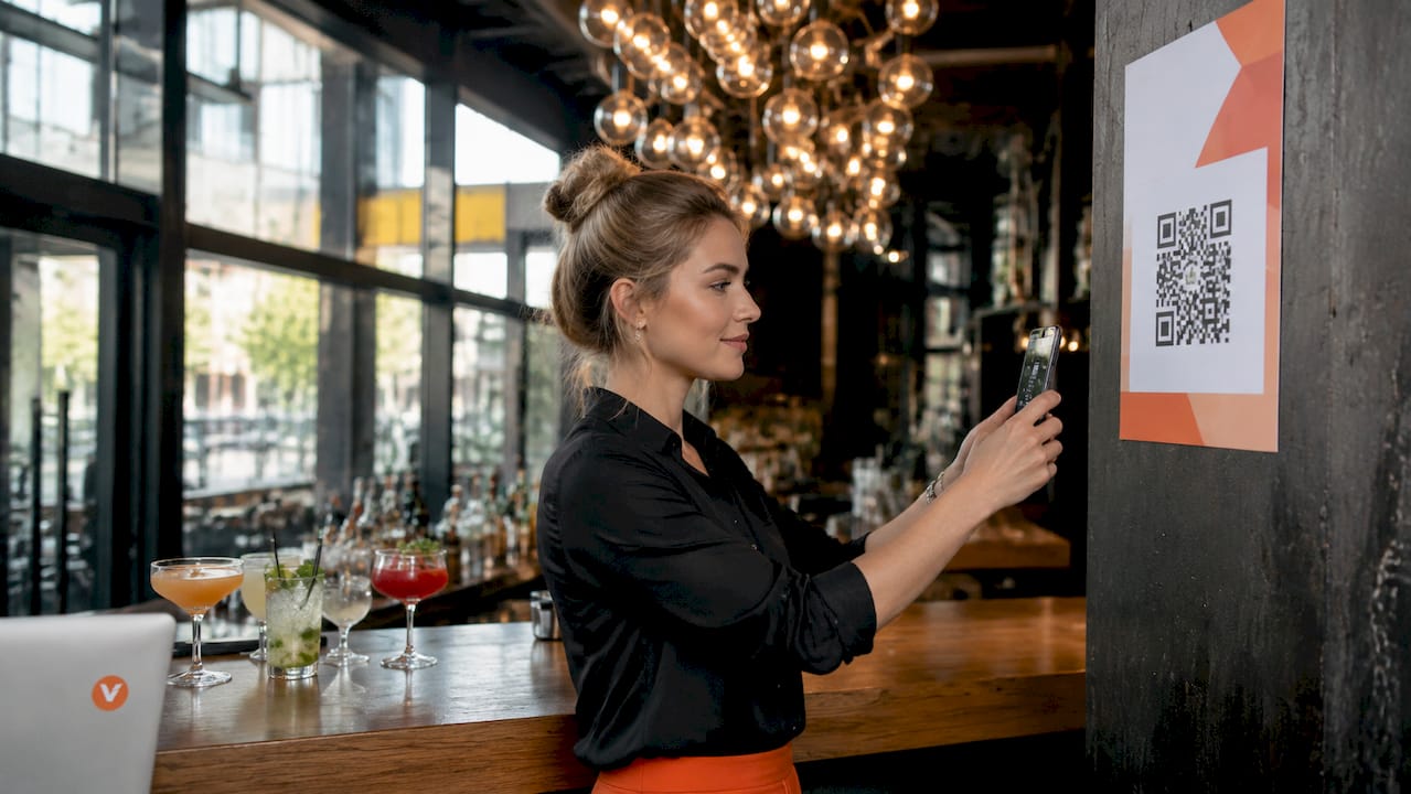 Een horecaondernemer scant de QR-code die op het tafeltje staat.