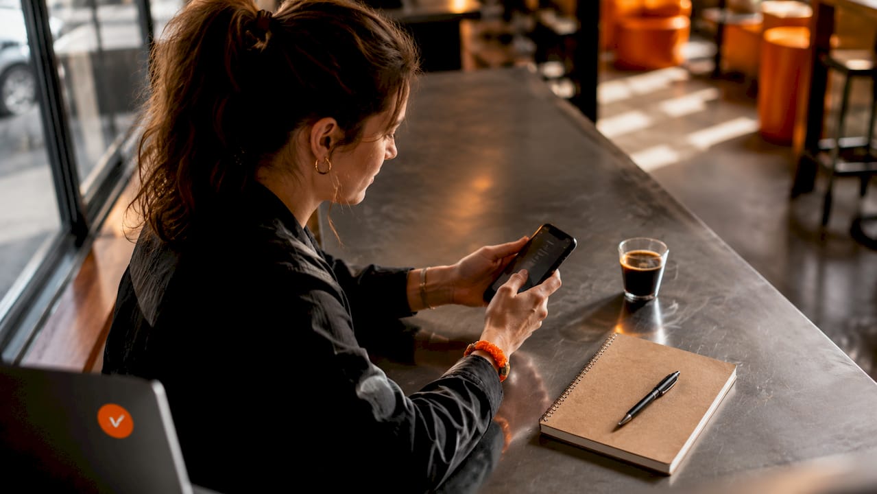 Een medewerker in de horeca bladert op zijn smartphone door de digitale menukaart.