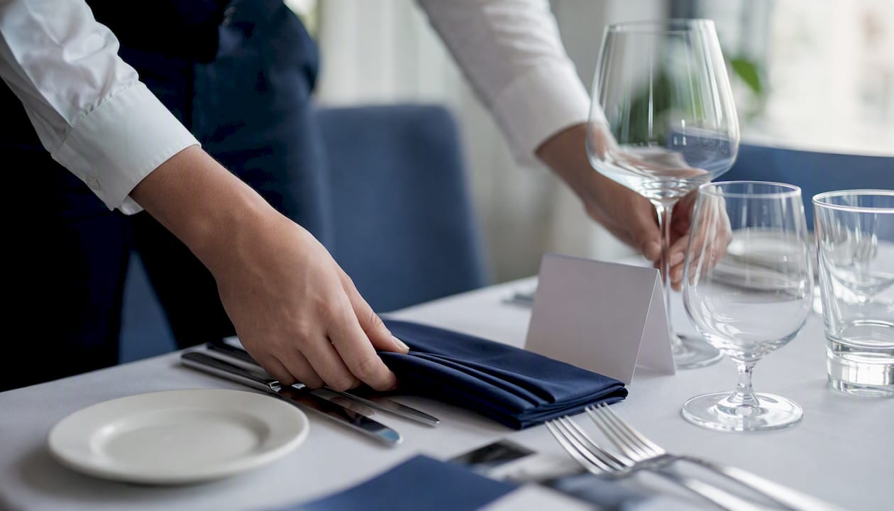 Hands arranging tableware at corporate event