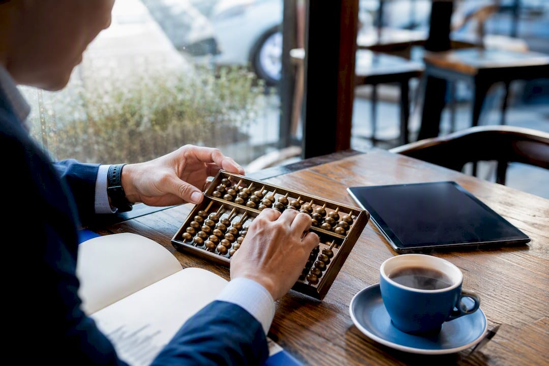 Hands tracing financial records on an abacus