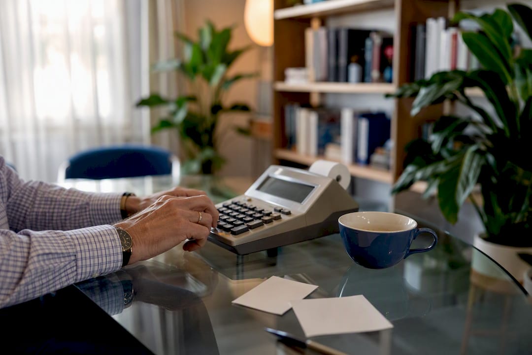 Hands calculating payroll deductions on adding machine
