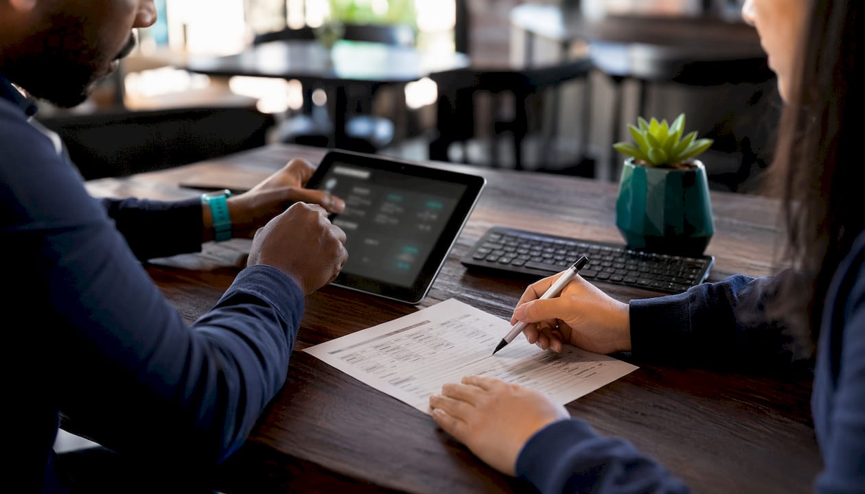 Hands managing payroll data on tablet and form