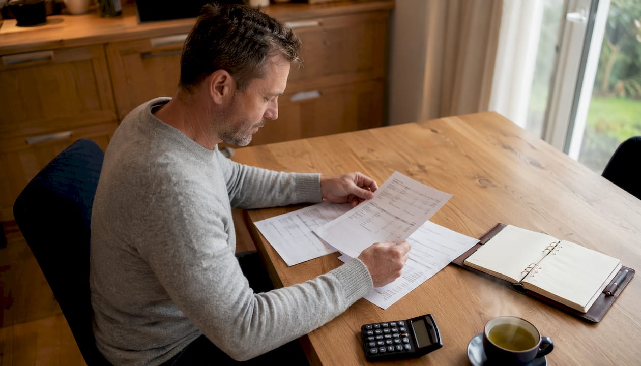 Self-employed man reviewing bank statements at desk