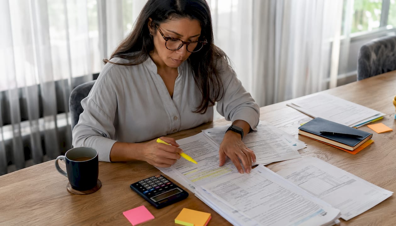 Woman organizing 1099 homebuying documents at table
