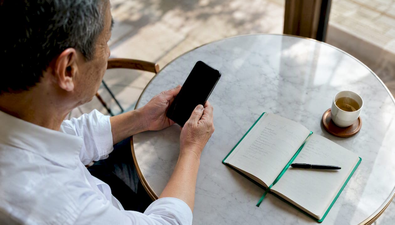 Hands holding phone with calendar and notes on desk