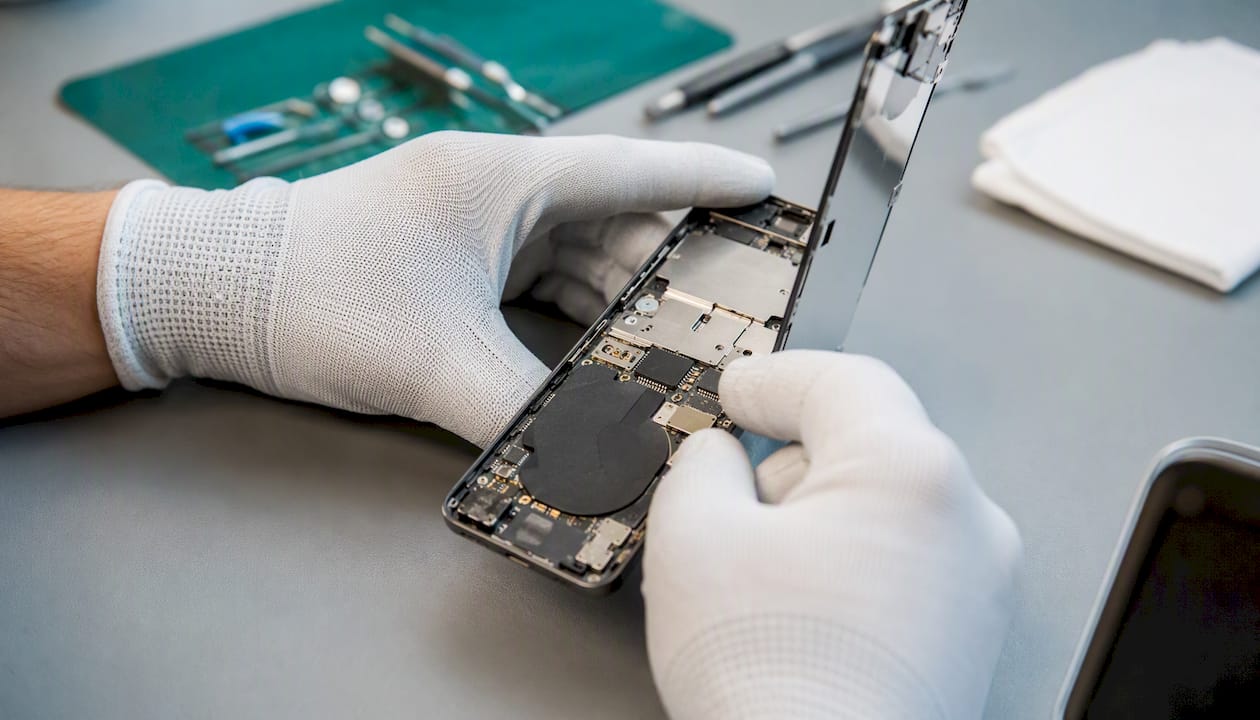 Hands inspecting phone internals for liquid damage