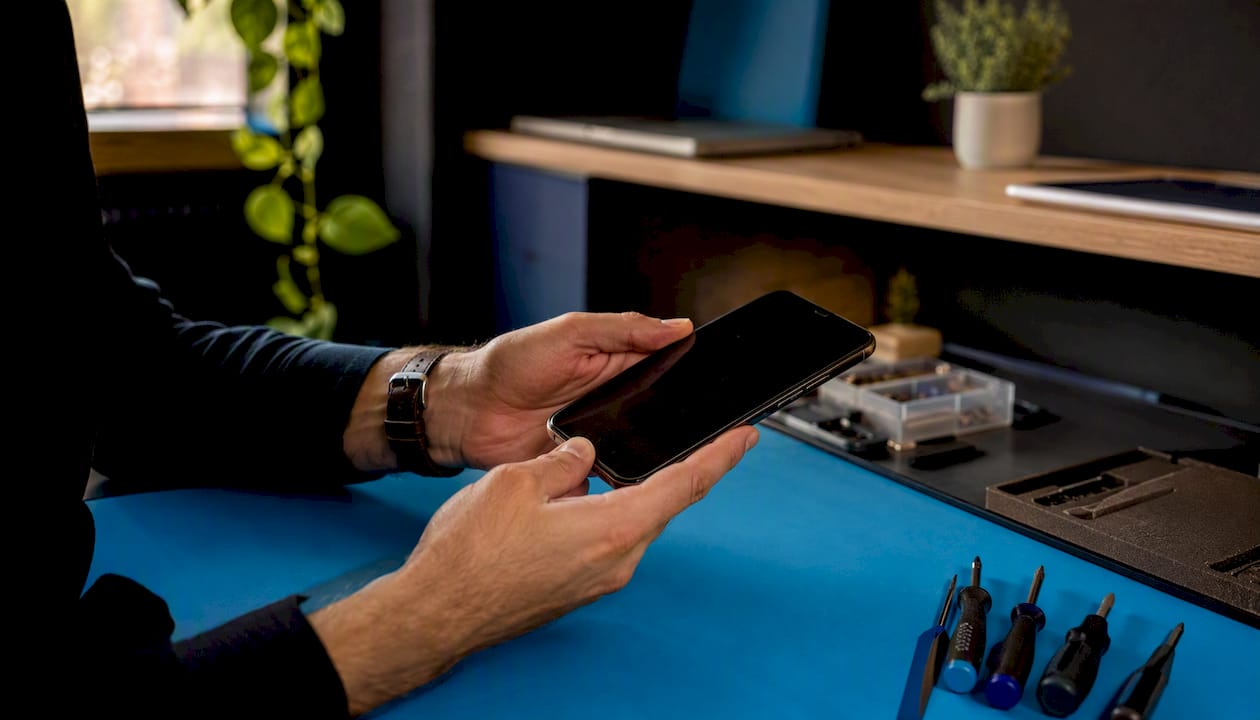 Hands inspecting refurbished smartphone edges