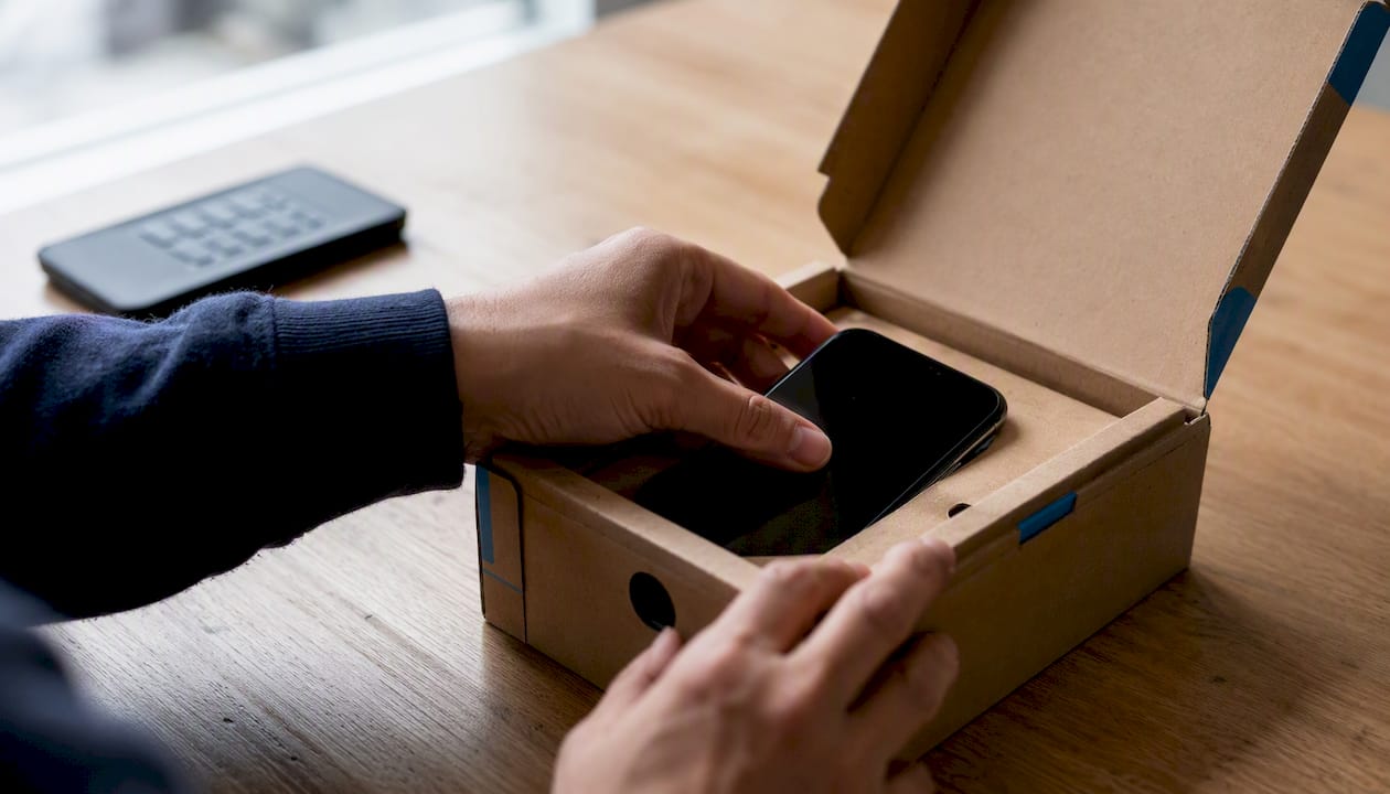 Hands unboxing a certified refurbished smartphone