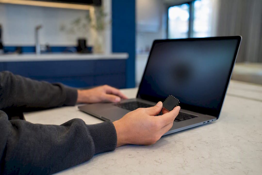 Hands pointing at laptop keyboard with chip model