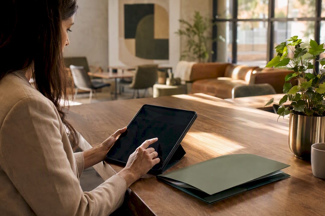 Hands holding tablet next to notebook and coffee