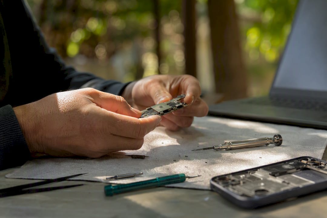 Hands inspecting broken smartphone components