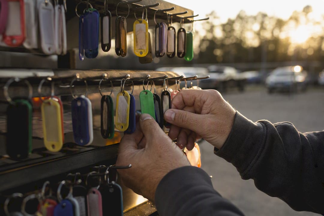 Hands managing vehicle key tags in dealership