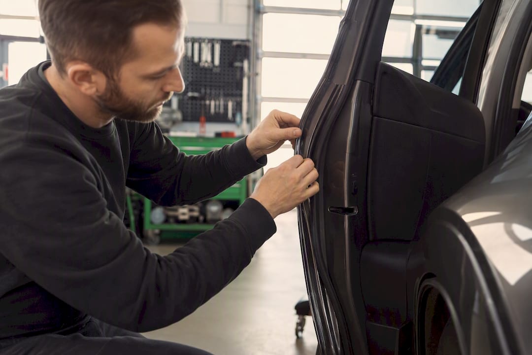 Technician fitting trim on vehicle door