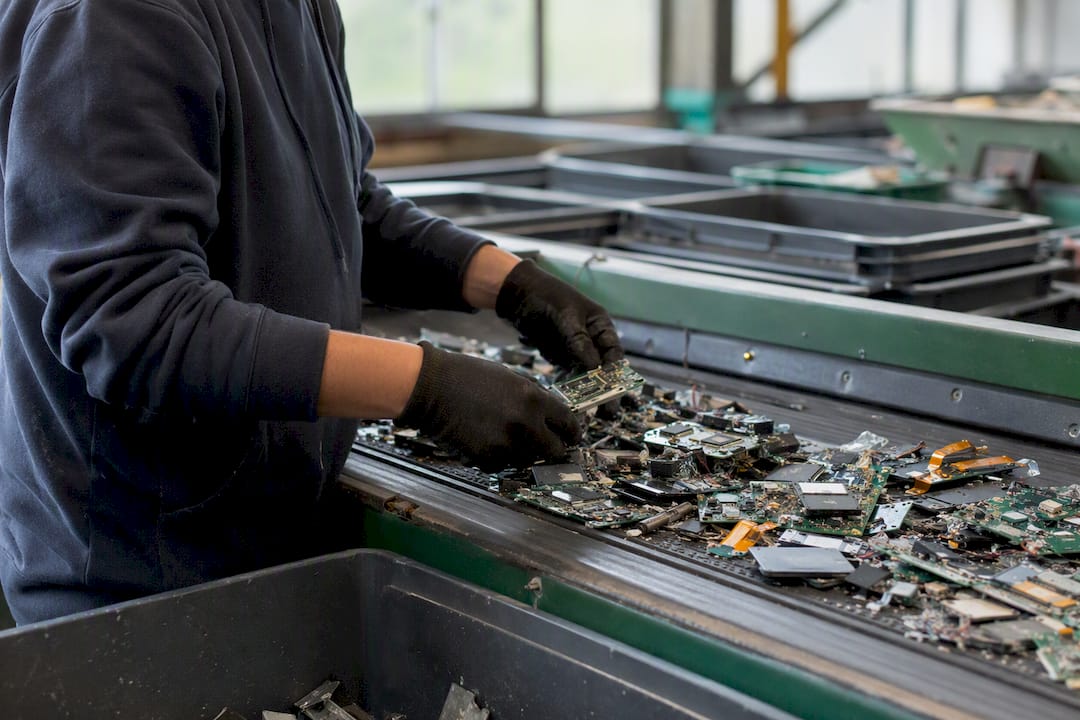 Hands sorting electronic waste at recycling facility