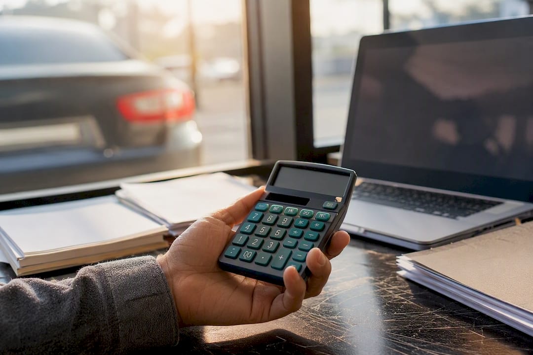 Hand using calculator at car dealership desk
