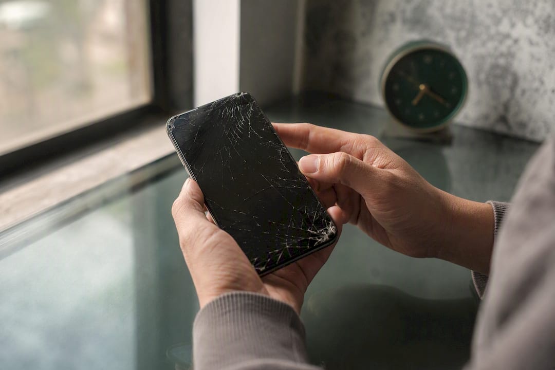 Hands inspecting cracked phone screen
