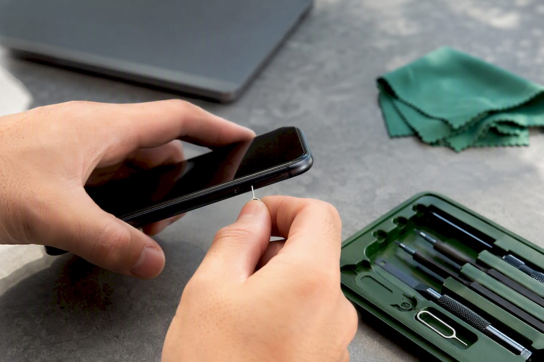 Hands ejecting SIM card tray from phone