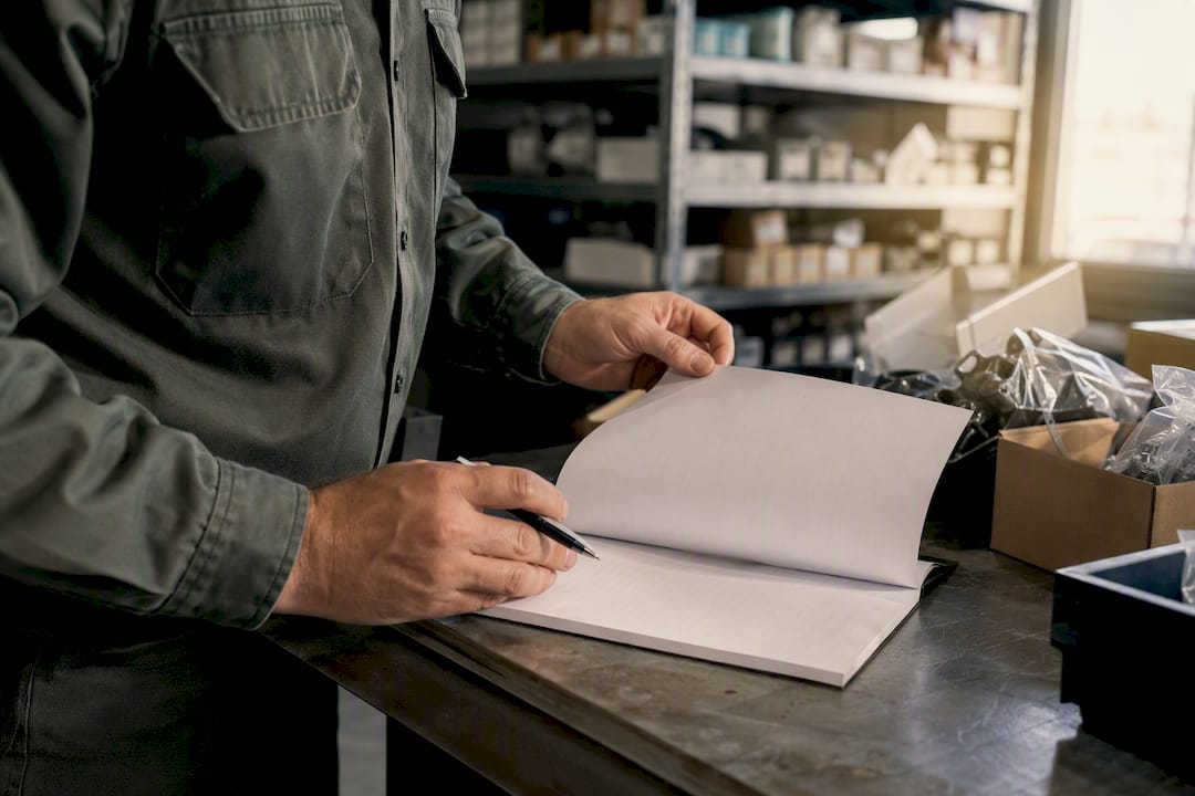 Hands checking blank receiving log at parts area