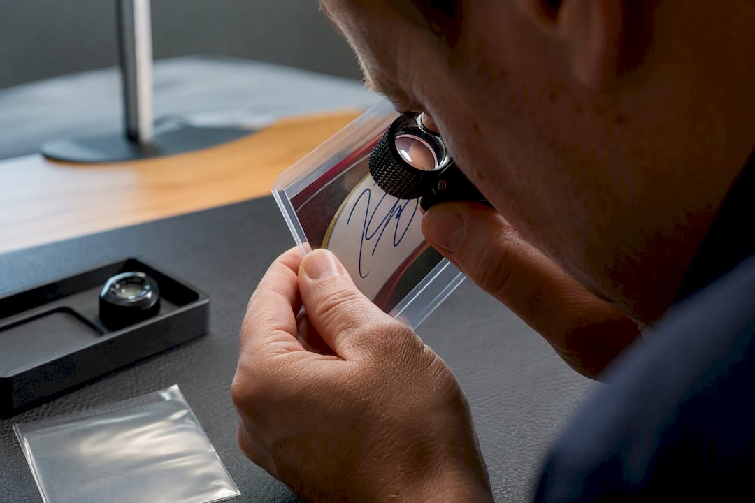 Authenticator inspecting a card autograph closely