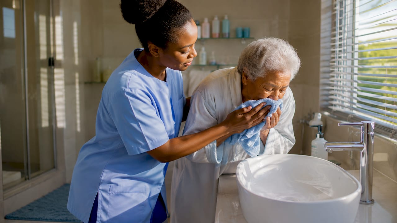 Caregiver assisting elderly woman with personal care