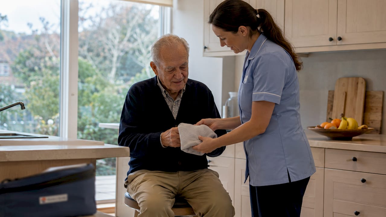 Caregiver aiding elderly man with daily hygiene