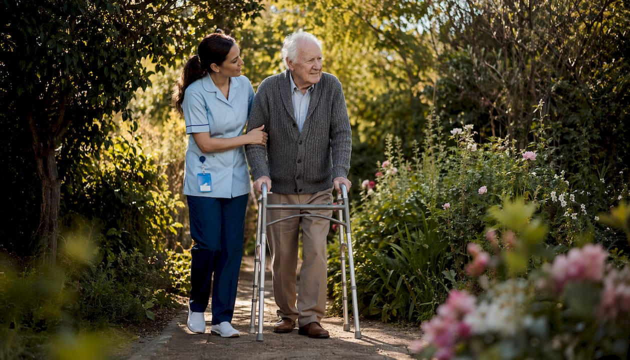 Caregiver assisting elderly man walking