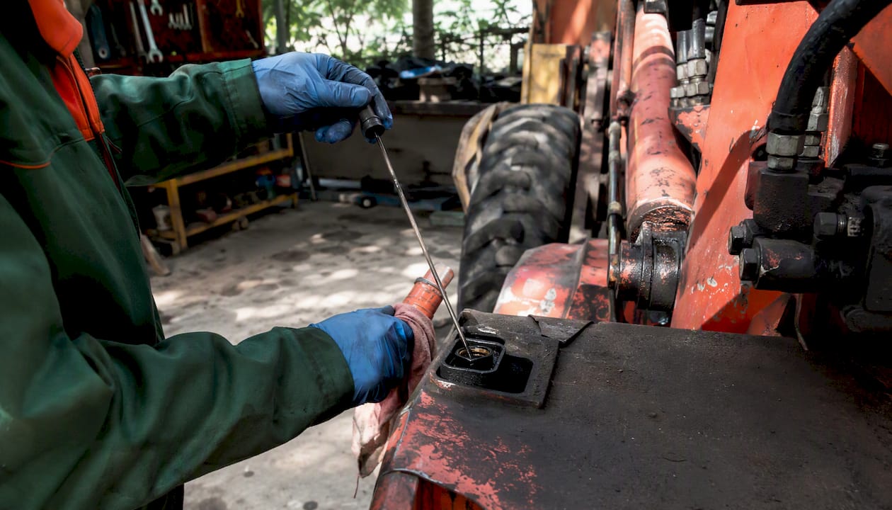 Technician inspecting used Terramite backhoe hydraulics