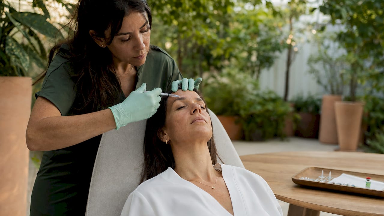 Nurse delivering botulinum toxin injection on forehead