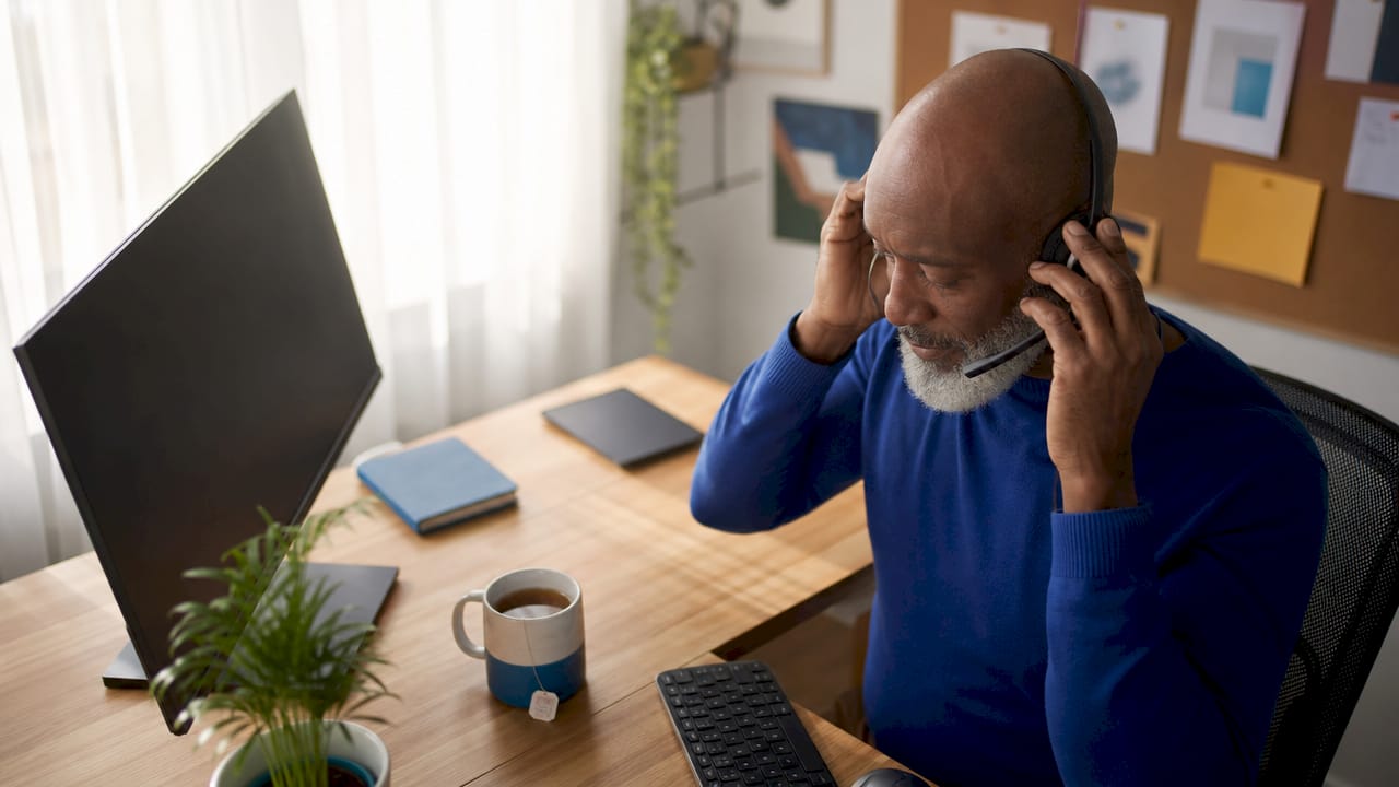 Customer service agent adjusting headset at desk