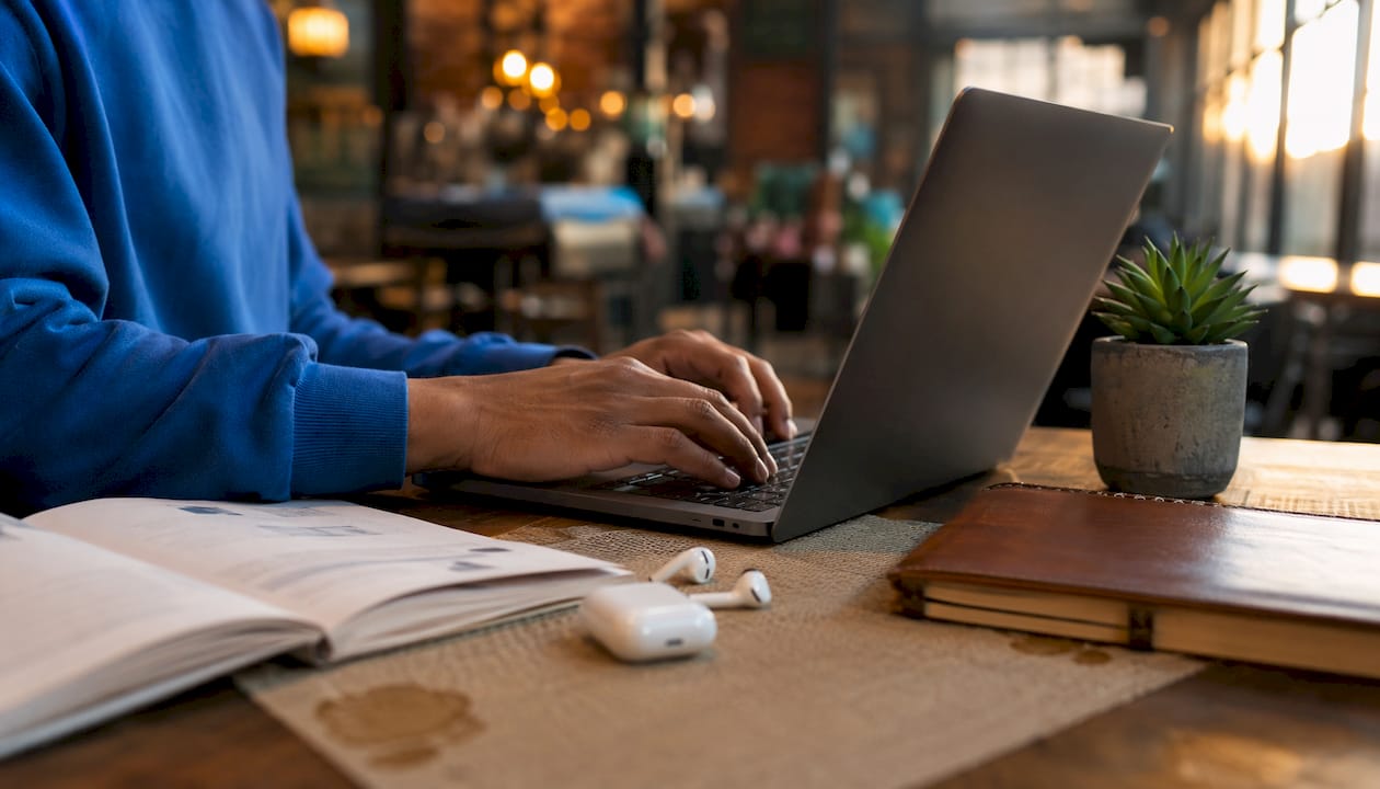 Close-up hands typing on laptop learning AI