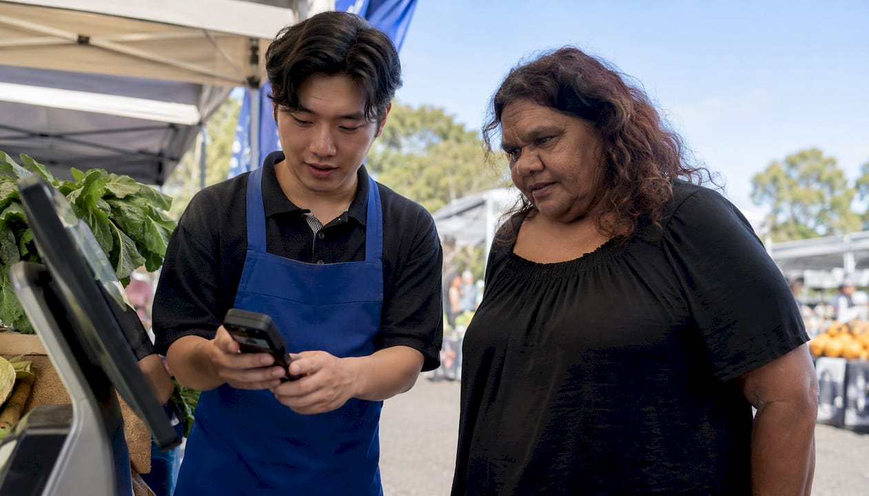 Retail employee assists customer using digital kiosk