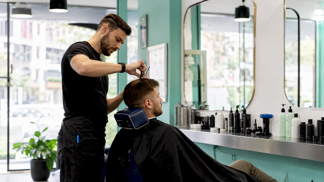 Barber trimming man's haircut close-up