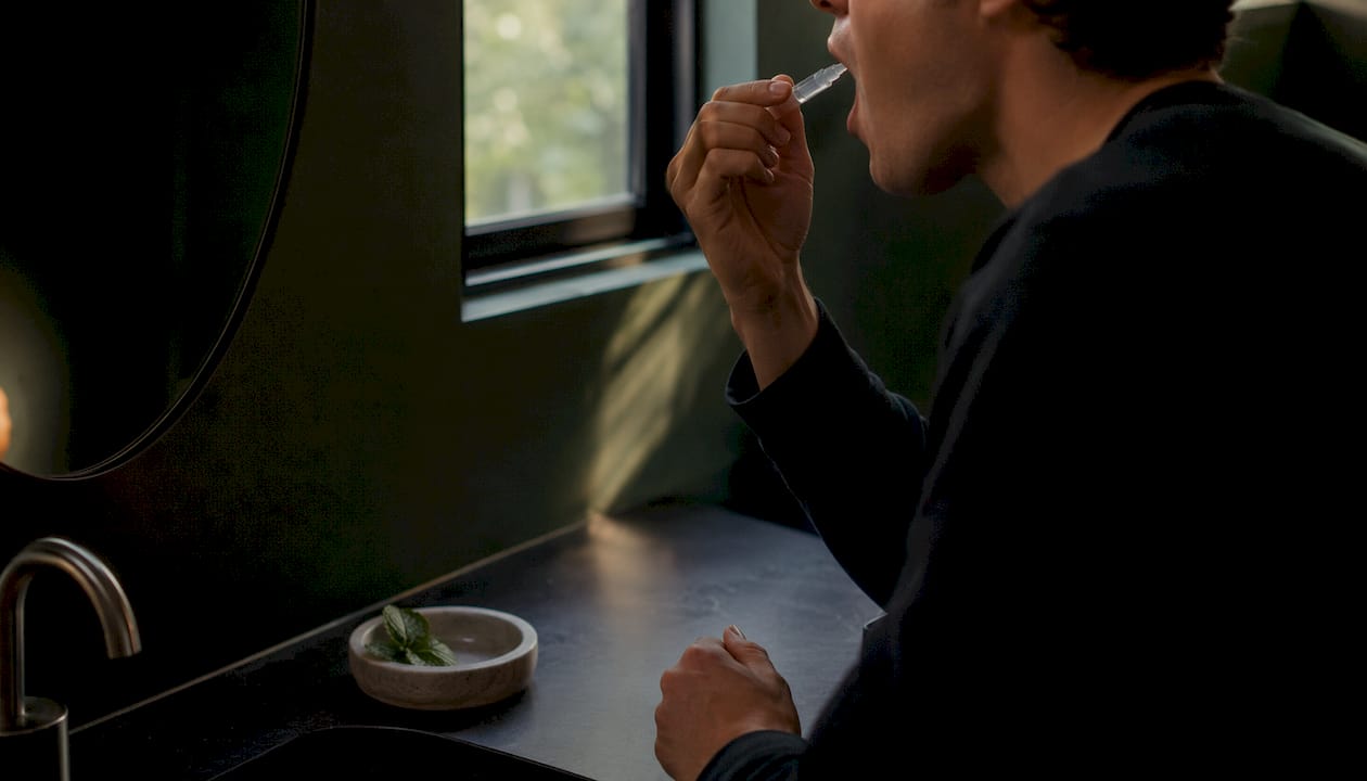 Close-up hands applying peppermint oral nicotine gel under tongue