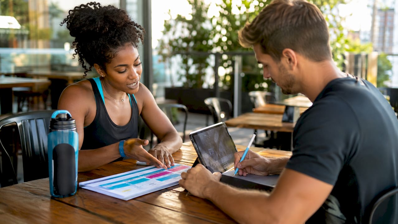 Coach and client reviewing workout plan at desk