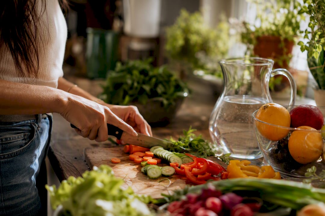 Hands chopping fresh vegetables in kitchen