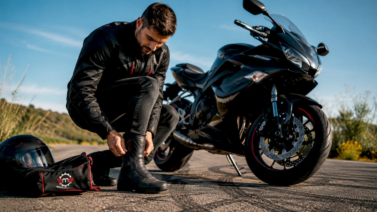 Motorcyclist adjusting ankle-protected boots in garage