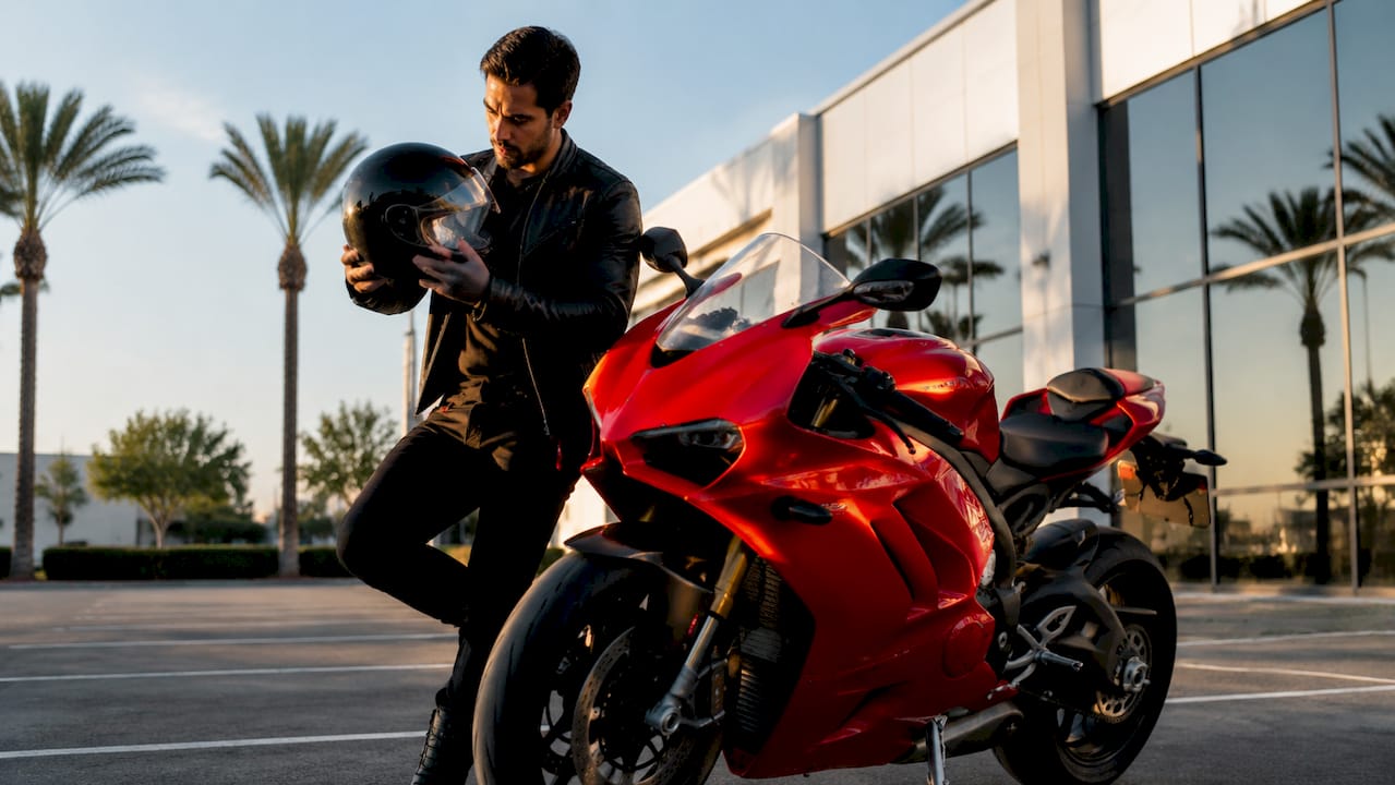 Motorcyclist inspecting clear helmet visor outdoors