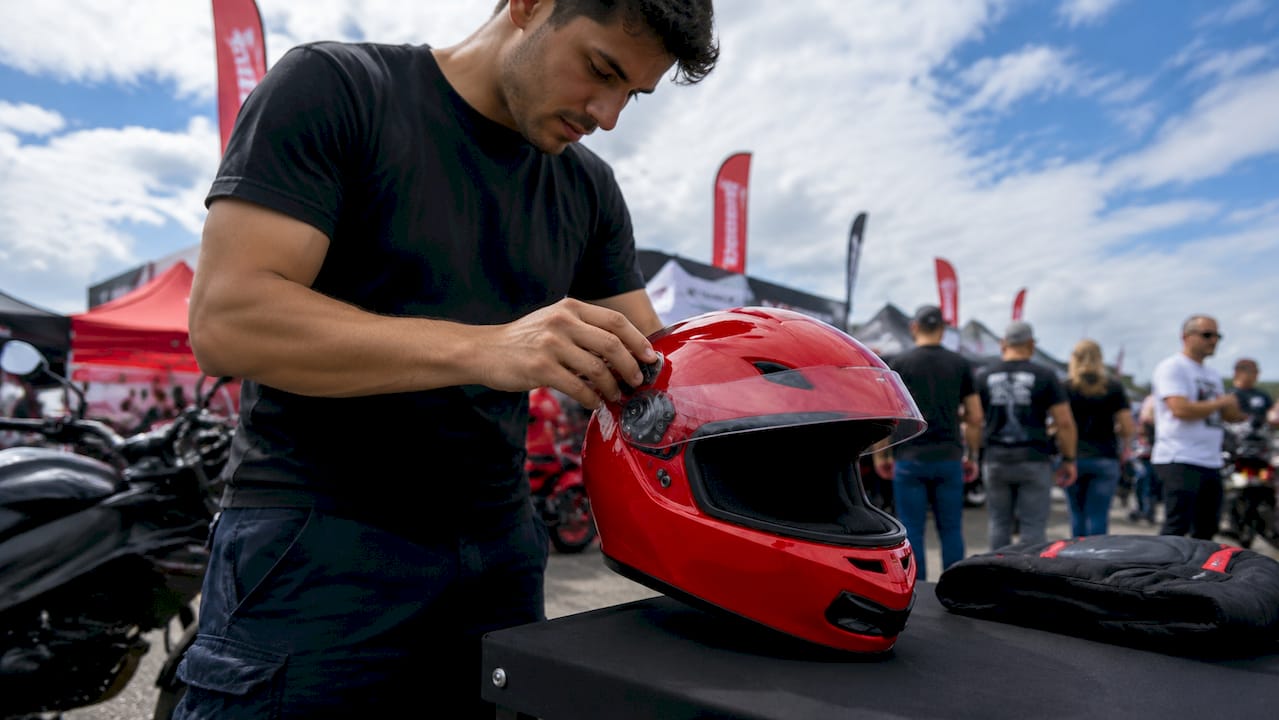 Hands attaching clear visor to motorcycle helmet indoors