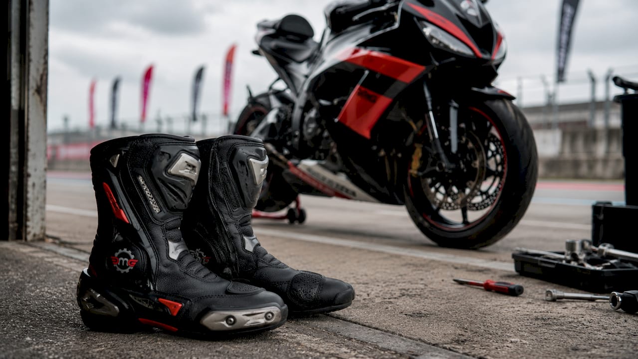 Pair of sportbike racing boots near motorcycle in workshop