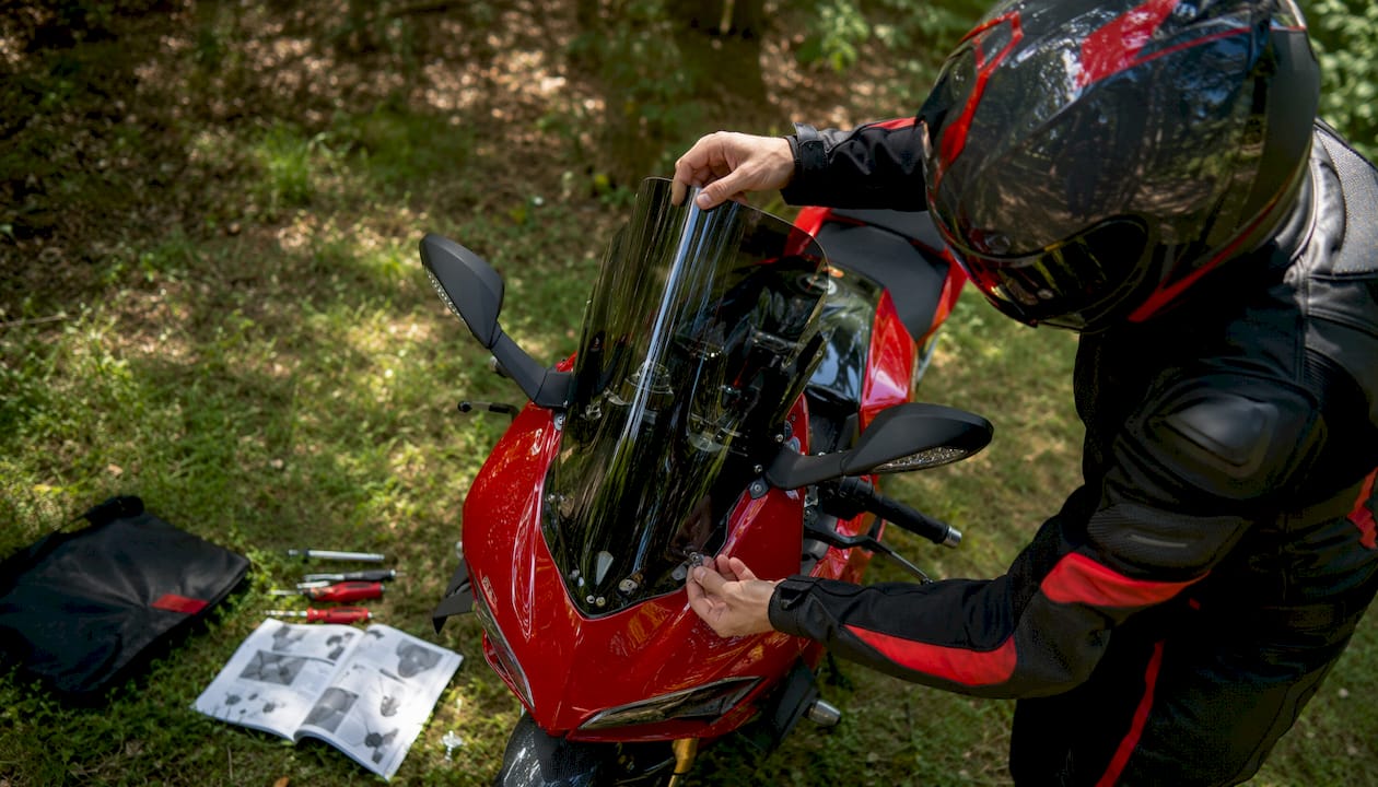Rider installing sportbike windscreen outdoors
