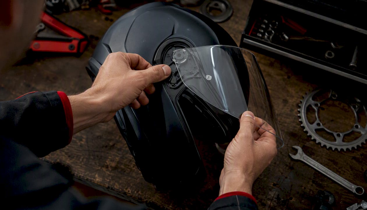 Hands removing helmet visor using quick-release