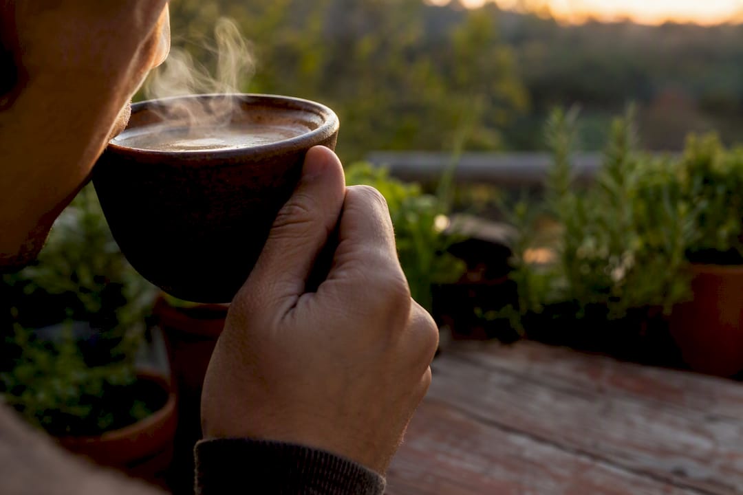 Hand holding cup taking sip of mushroom coffee