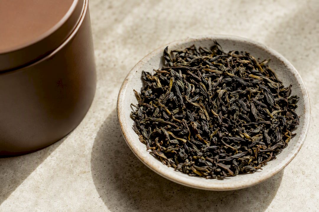 Whole loose-leaf tea beside storage tin