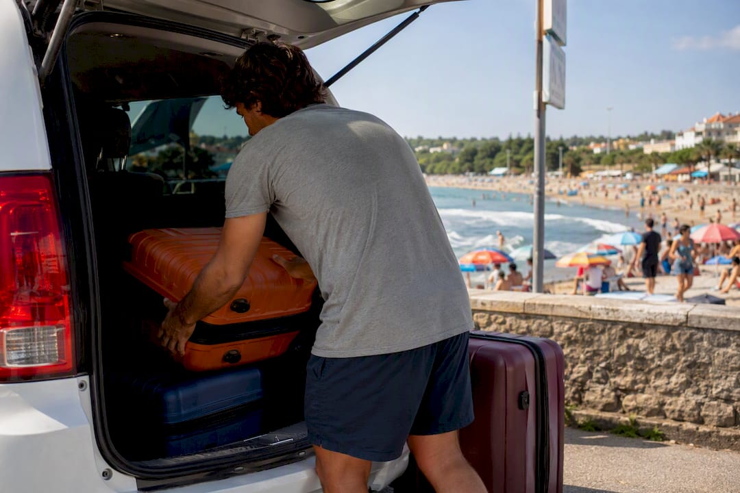 Hands loading luggage into a minivan