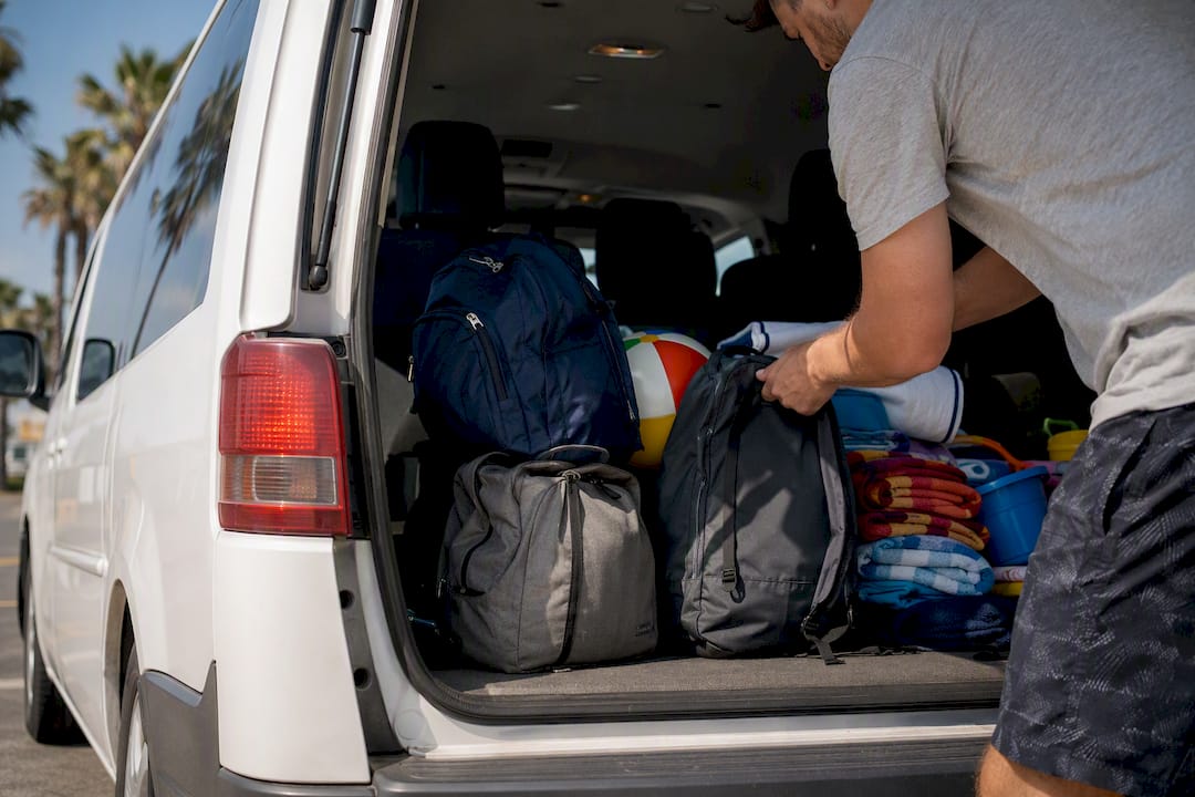 Hands loading luggage in van cargo area