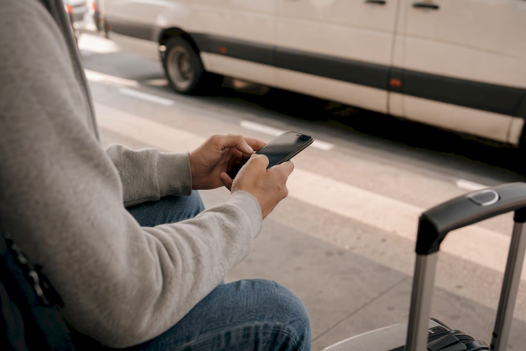 Hands texting near airport curbside van