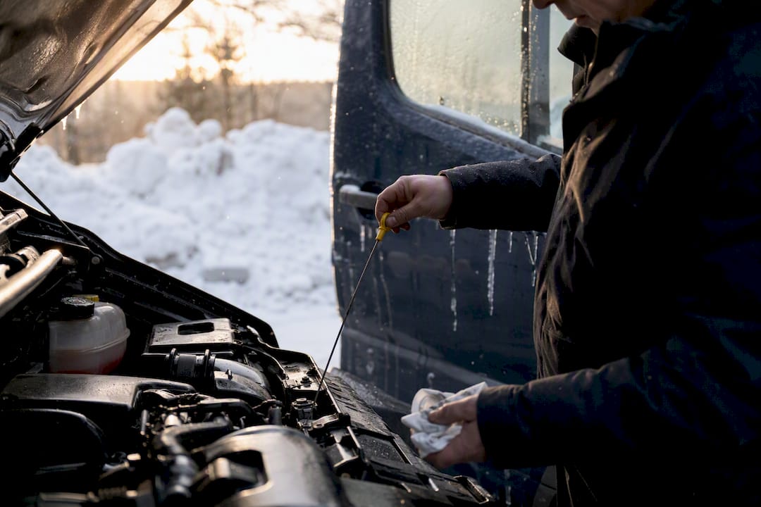 Hands checking tire pressure on frosted van tire