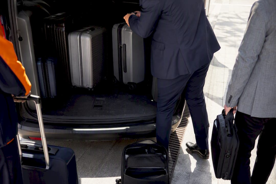 Hands loading luggage into large passenger van